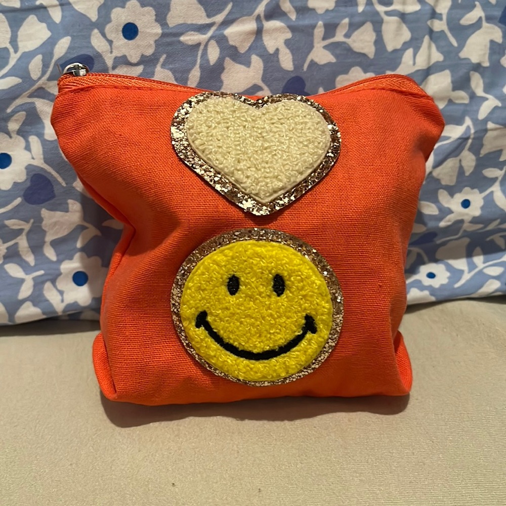 A cute mini orange bag with stickers perfect for small accessories and makeup.
